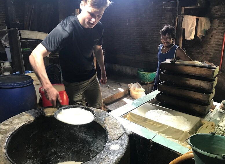 A person stirring a large cooking pot in a rustic kitchen setting. 3