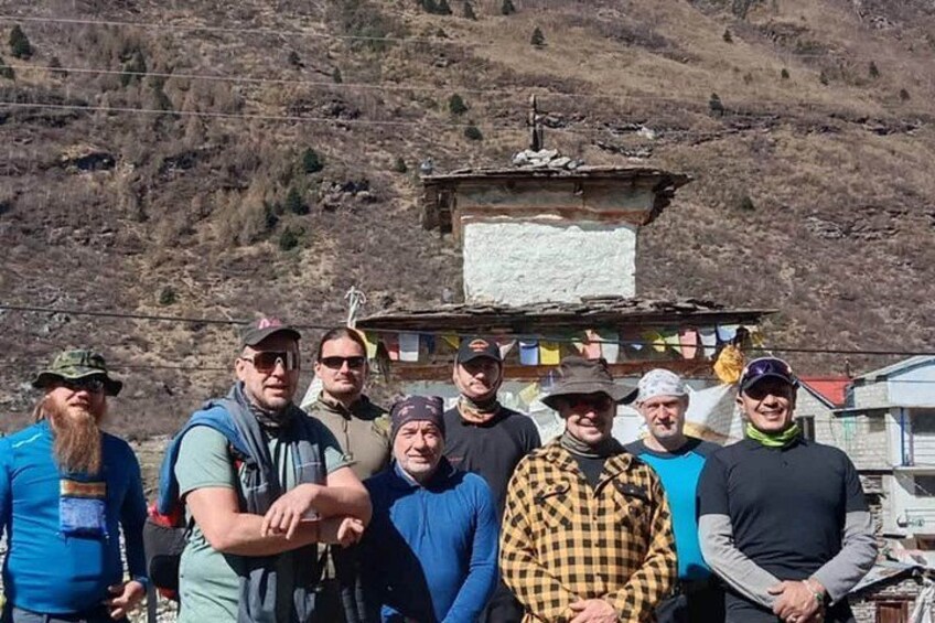 A group of people standing in a mountainous area with a small building in the background. 2