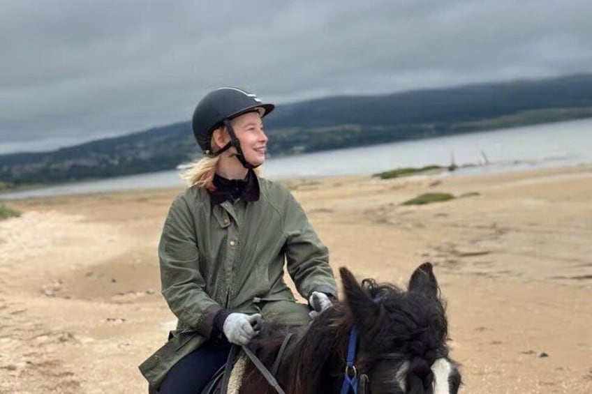 A person riding a horse on a beach with a cloudy sky in the background. 5