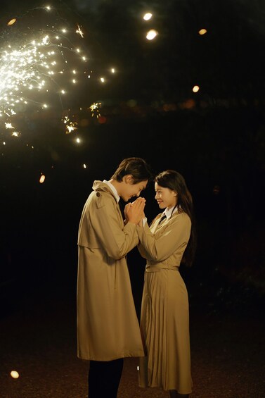Two people in matching uniforms standing close together with their hands clasped. 2