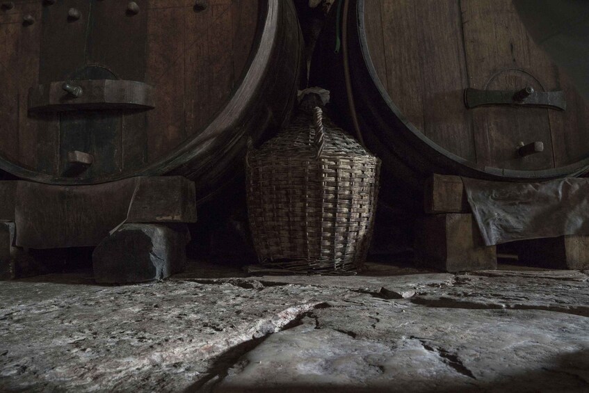 A rustic cellar with wooden barrels and a woven basket on the floor. 3