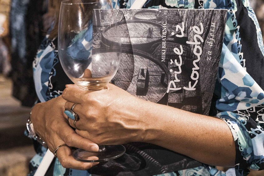 A person holding a wine glass with a label that reads 'Mik B. Trichel & Kanobe.' 5