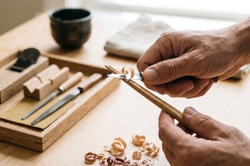 Hands using chopsticks to pick up food scraps on a wooden table. 3