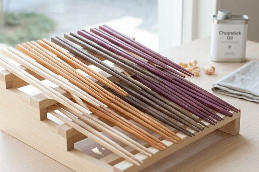 A wooden chopstick holder with various colored chopsticks. 4