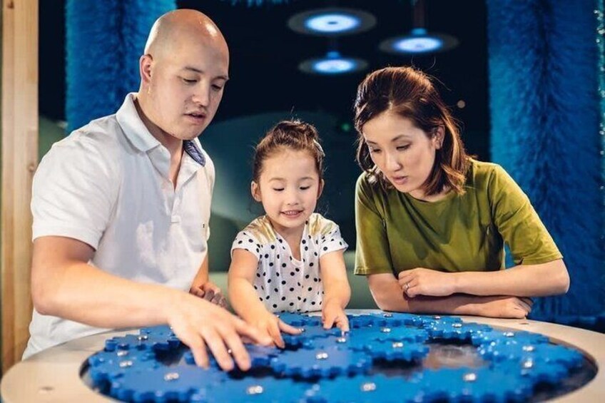 Three people sitting at a table with a blue circular object. 2