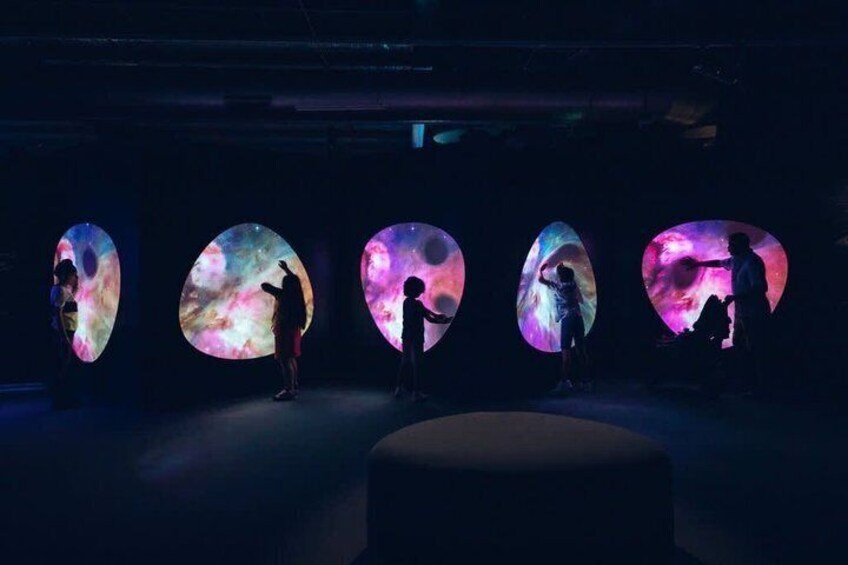 A dark room with five illuminated circular projections on the wall, each displaying a different celestial scene. 4