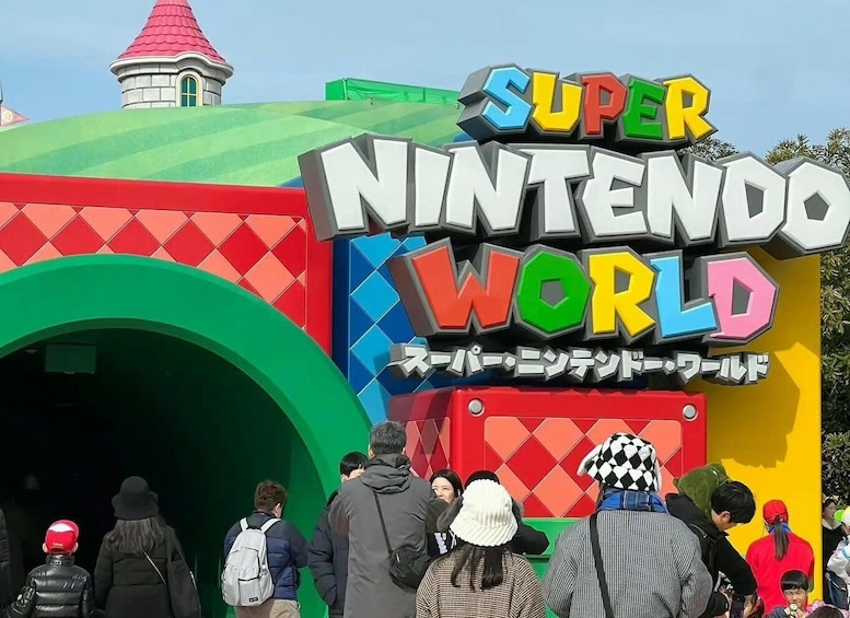 A colorful entrance to Super Nintendo World with a red and green archway and a tower in the background. 3