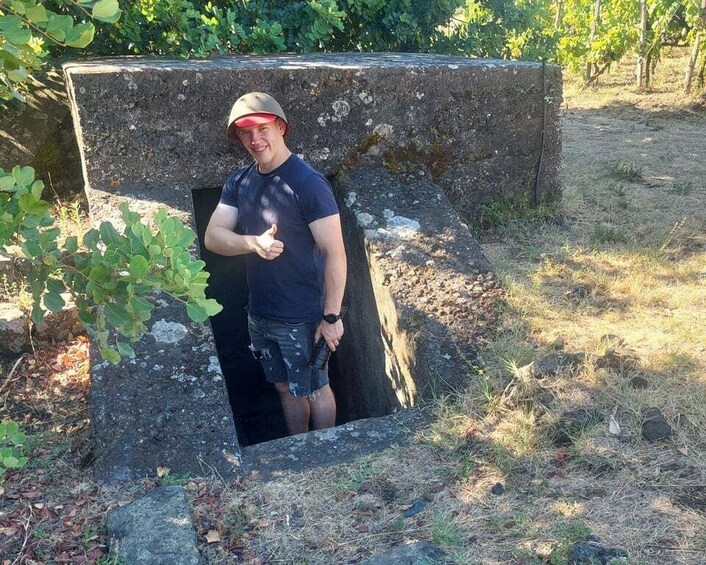 A person standing in a stone structure with a thumbs-up gesture. 5