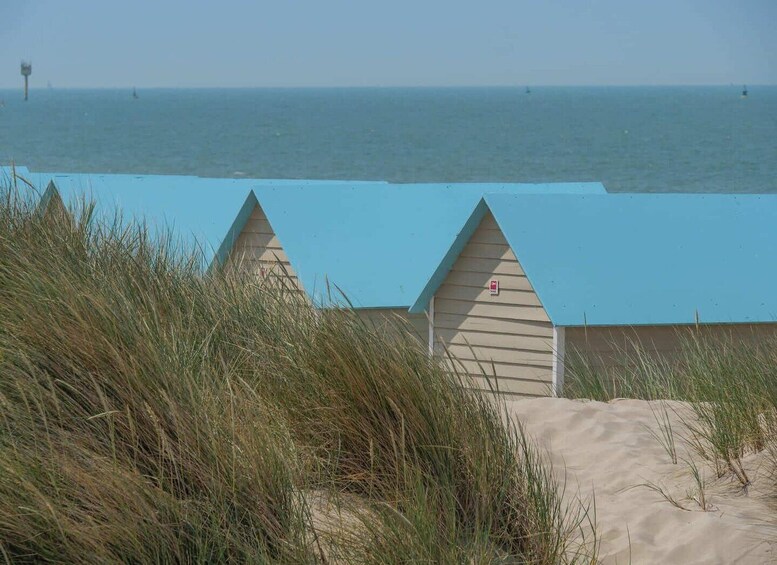 A beach with sand dunes and a blue-roofed building. 5