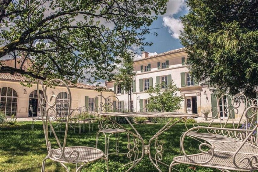 A courtyard with wrought iron furniture, a building with arched windows, and lush greenery. 2