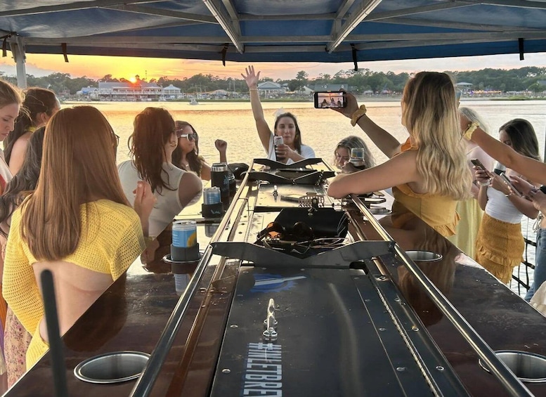 A group of people on a boat with a grill and drinks, enjoying a sunset. 3