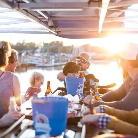 A group of people sitting at a table on a boat with a sunset in the background. 4