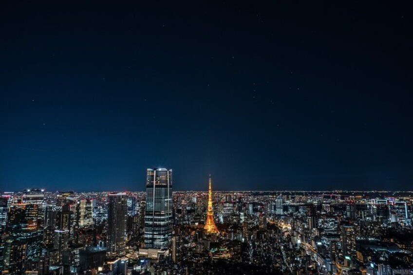 A nighttime cityscape with illuminated buildings and a prominent tower. 5