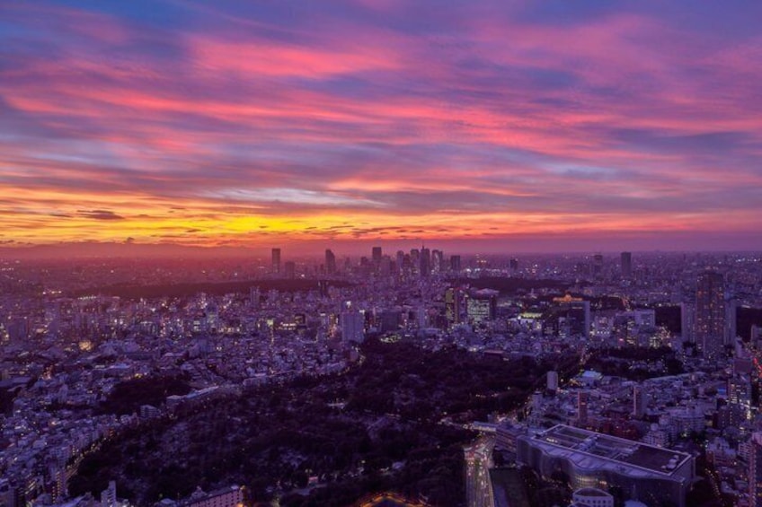 A cityscape at sunset with a colorful sky, dense urban buildings, and a river. 1