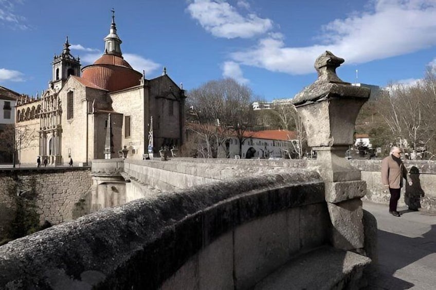 A stone bridge with a stone balustrade, a church with a red dome, and a clear blue sky. 4
