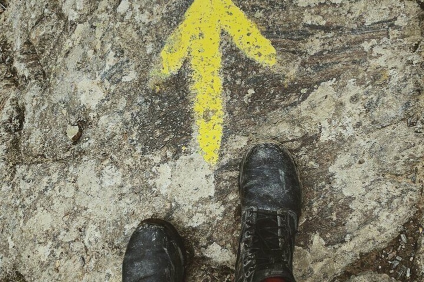 A pair of black shoes on a rough, textured surface with a yellow arrow pointing upwards. 1