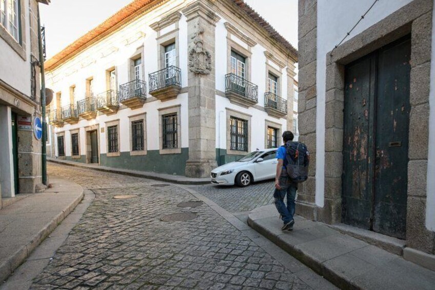 A cobblestone street, a white building with balconies, and a person walking. 3