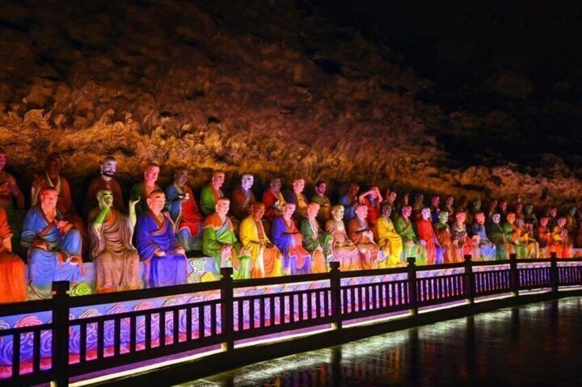 A row of colorful statues along a riverbank at night. 5