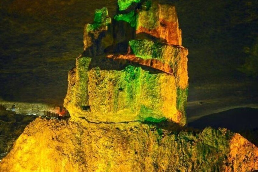 A brightly lit rock formation with a bridge in the background. 4