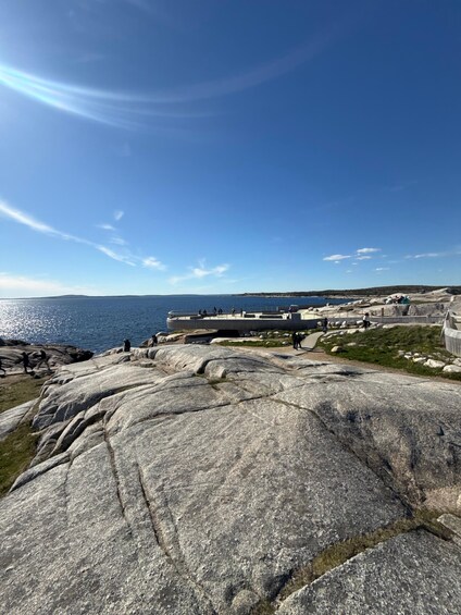 A rocky landscape with a clear blue sky and the ocean in the background. 2
