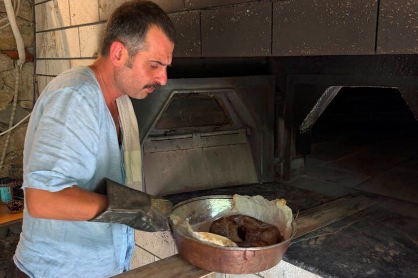 A person working with a large metal bowl and a tool in a rustic kitchen setting. 1