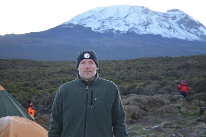 A person standing in a natural landscape with a snow-capped mountain in the background. 3