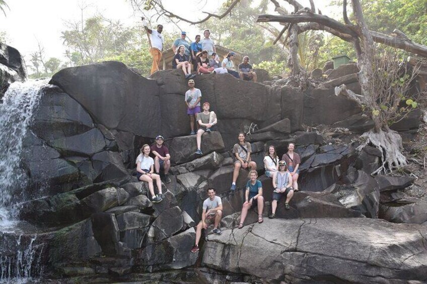 A group of people sitting on rocks near a waterfall. 3