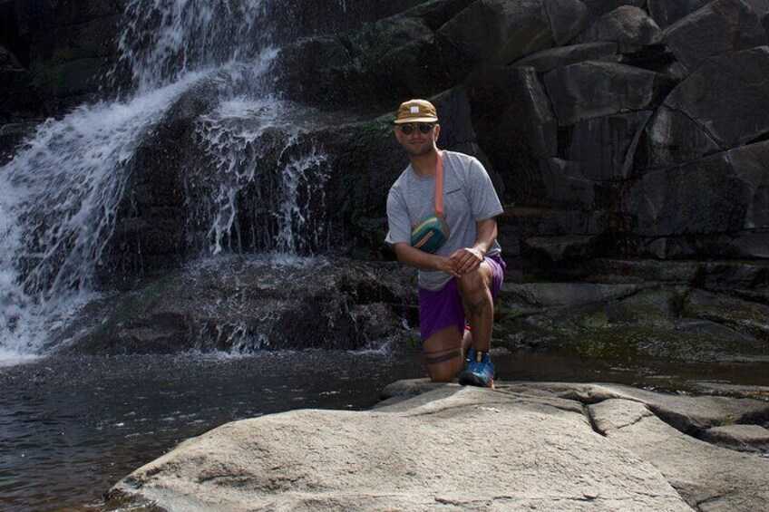 A person sitting on a rock by a waterfall. 2