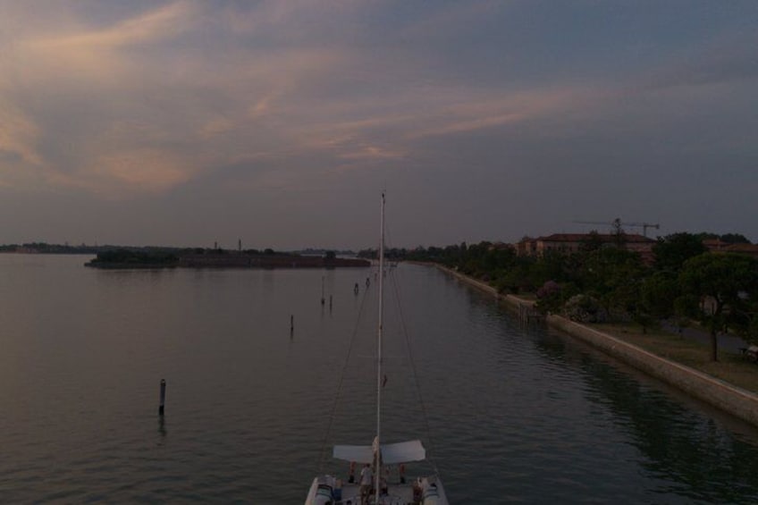 A calm river with a boat, a distant shoreline, and a clear sky. 3