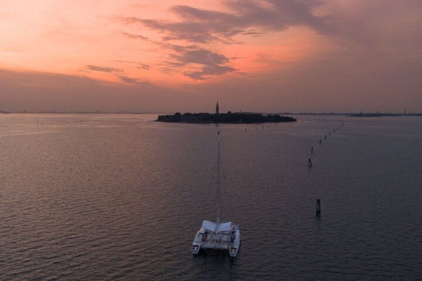 A sailboat on calm waters during sunset with a distant island and a clear sky. 4