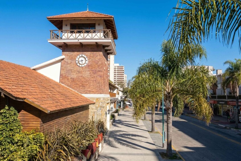 A street with a clock tower, palm trees, and buildings. 5