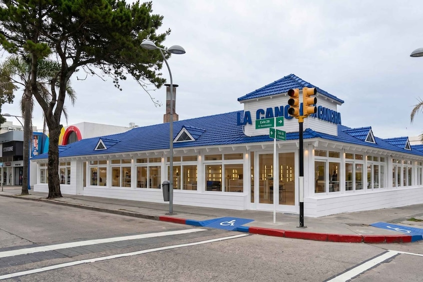 A restaurant named 'La Cancha' with a blue roof and white walls, located at an intersection with a traffic light and a pedestrian crossing. 3
