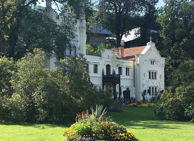 A white building with a red roof, surrounded by lush greenery and a well-maintained garden. 3