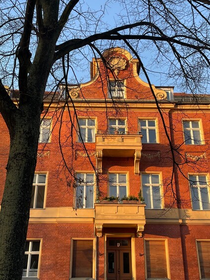 A red brick building with a balcony, windows, and a door. 2