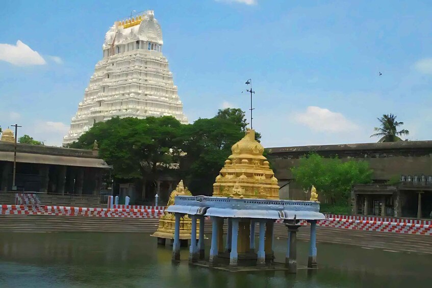 A temple complex with a large white tower and golden shrines. 3