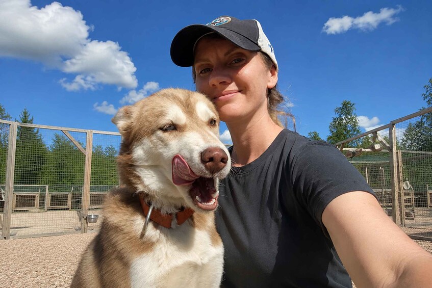A person with a dog in a fenced area with trees and a clear sky. 2