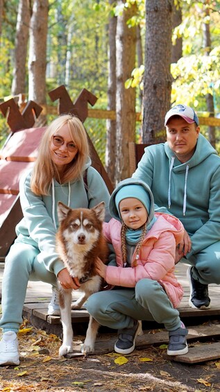 A family with a dog in a forested area with wooden structures. 1