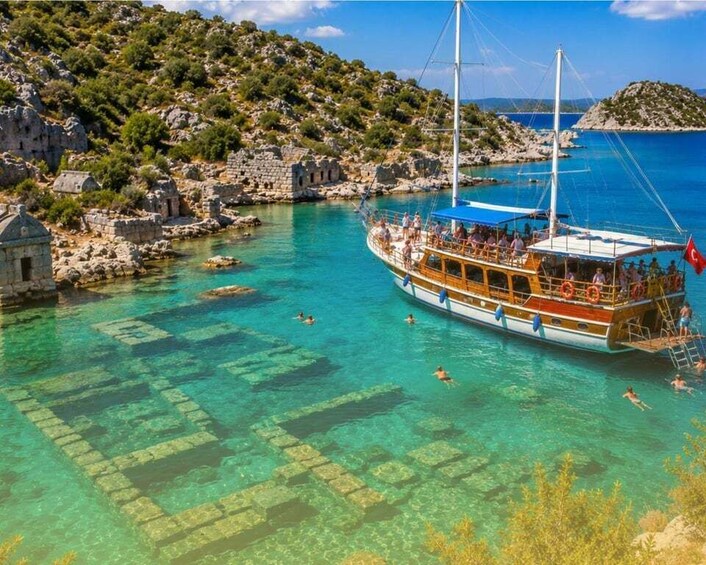 A boat with people on it near a clear blue sea, rocky shore, and a small island. 5