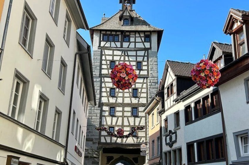 A traditional half-timbered building with a tower, surrounded by other buildings with white facades. 5