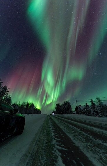 A road with a car, snow-covered landscape, and the Northern Lights. 2