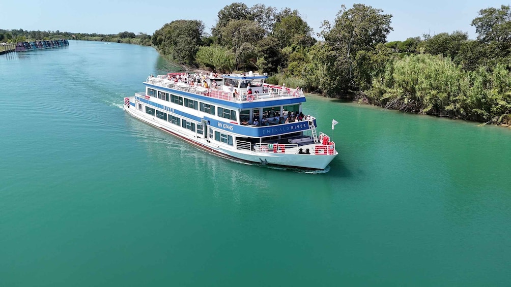 A riverboat named 'Emerald River' with passengers on deck, surrounded by lush greenery. 5