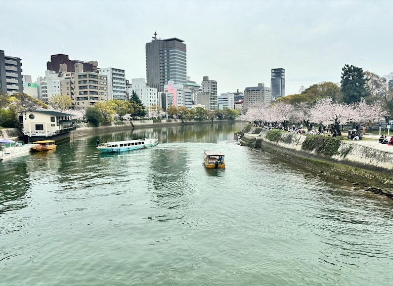 A river with boats, a city skyline, cherry blossoms, and a bridge. 3