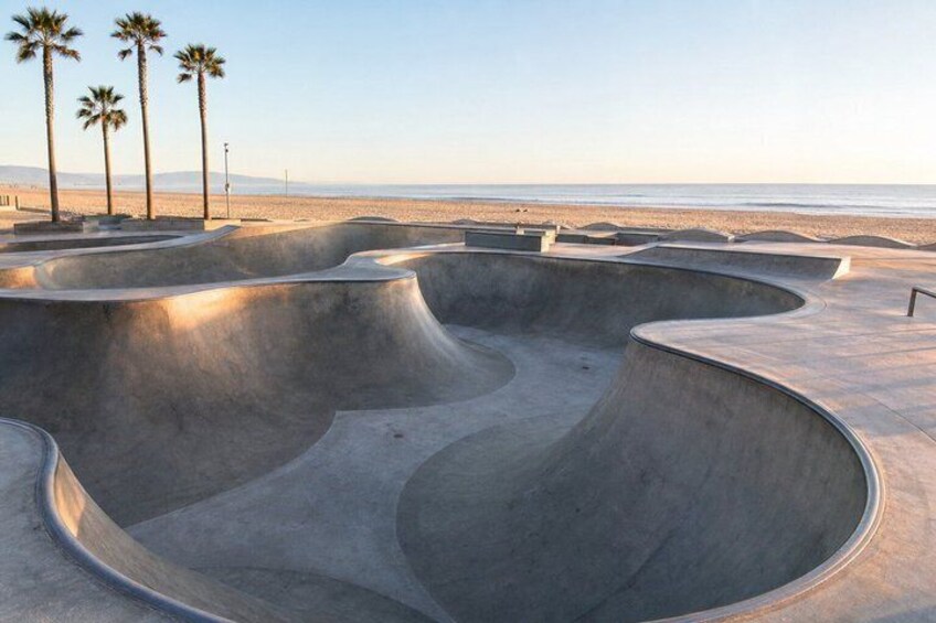 A skate park with curved ramps and palm trees in the background. 2