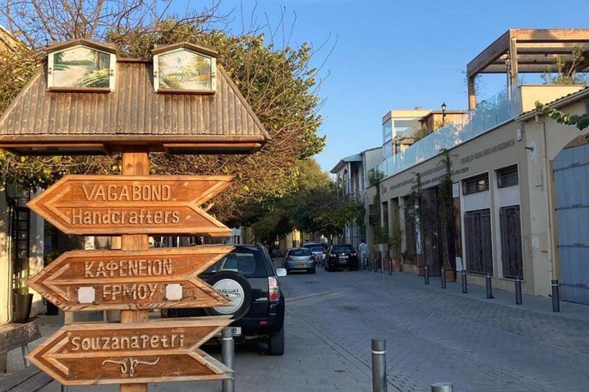 A street with wooden directional signs, parked cars, and buildings. 5