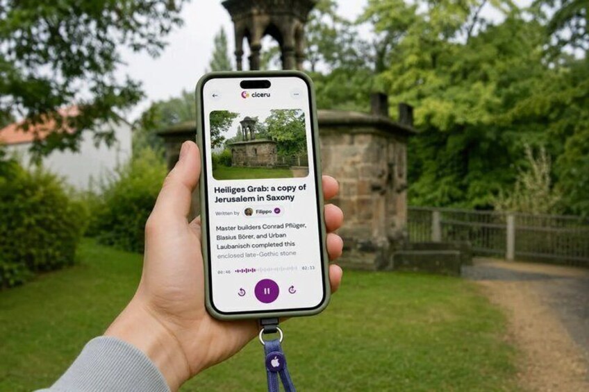 A hand holding a smartphone displaying a photo of a historic building with a caption. 1