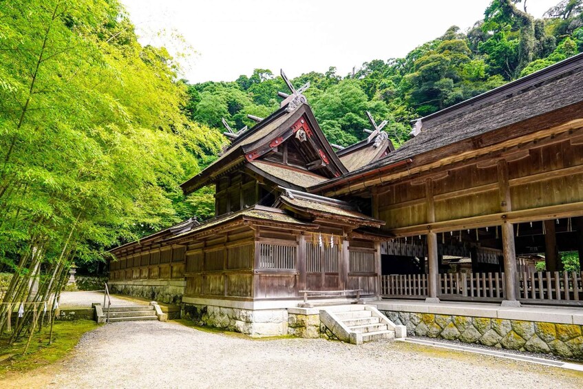 A traditional Japanese building with a sloped roof and wooden construction, surrounded by lush greenery. 3