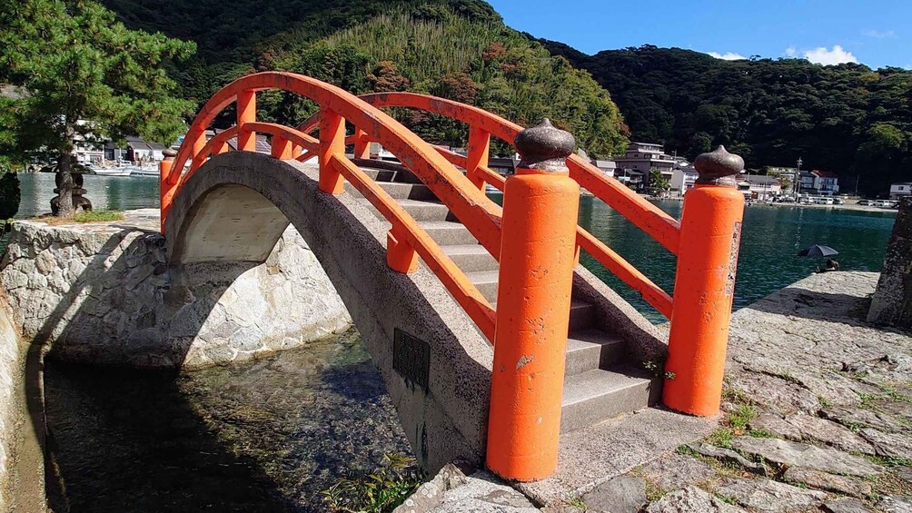 A stone bridge with orange railings over a body of water. 4