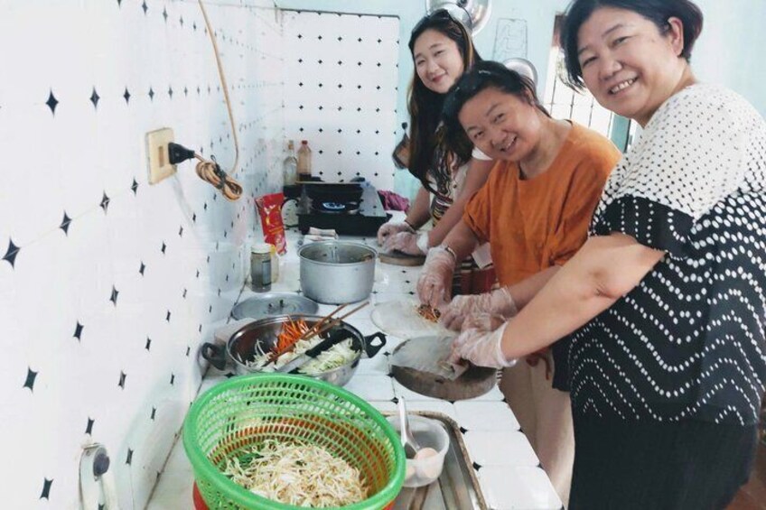 A kitchen with people cooking, a green basket, and a white tiled wall. 5