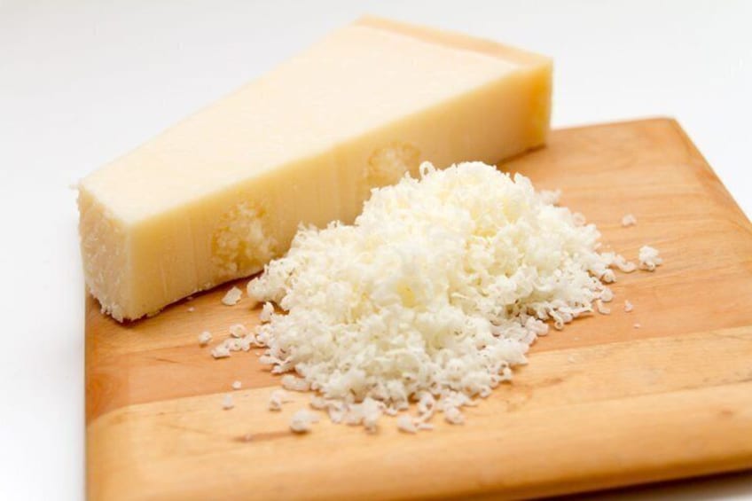 A block of cheese and grated cheese on a wooden cutting board. 2