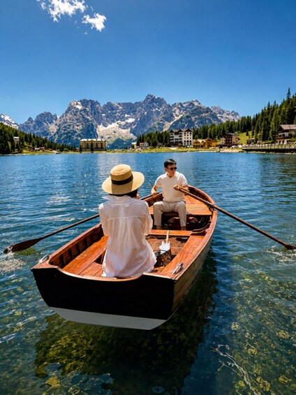 A wooden rowboat on a clear lake with mountains in the background. 1